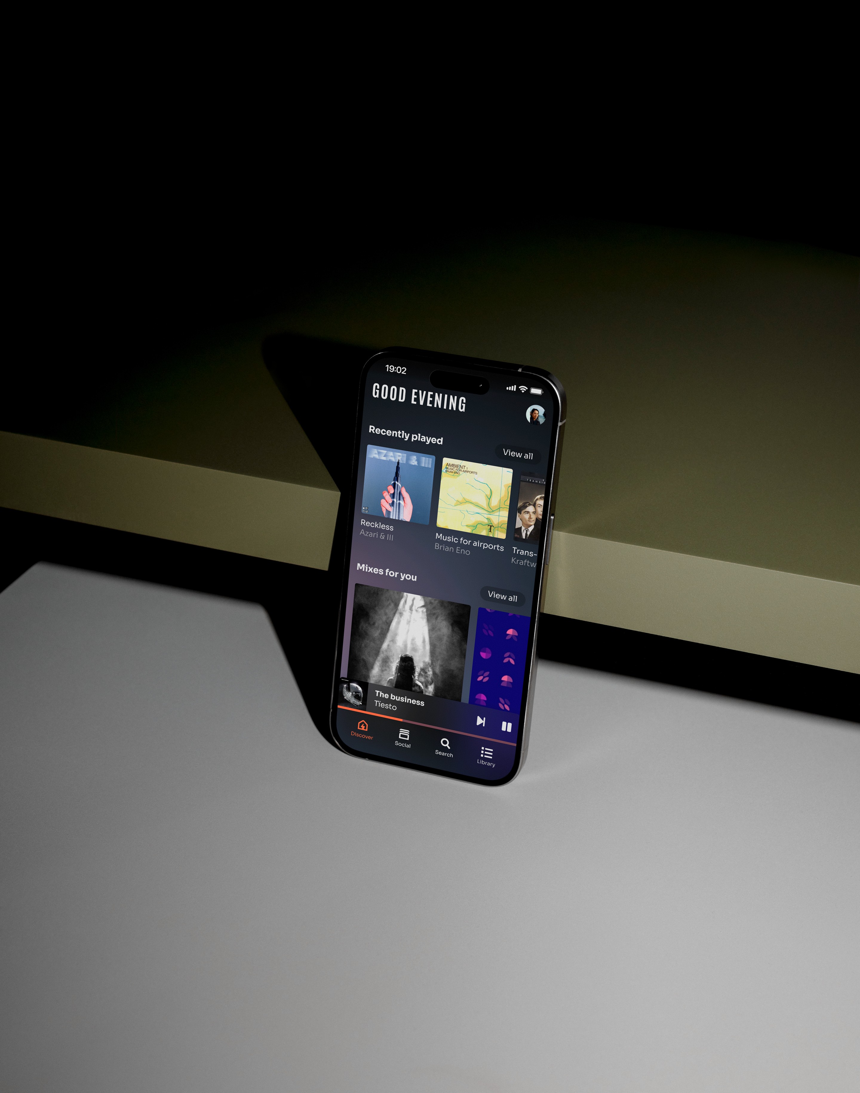 Macbook displaying a design, placed on a wooden table with beige curtains in the background.